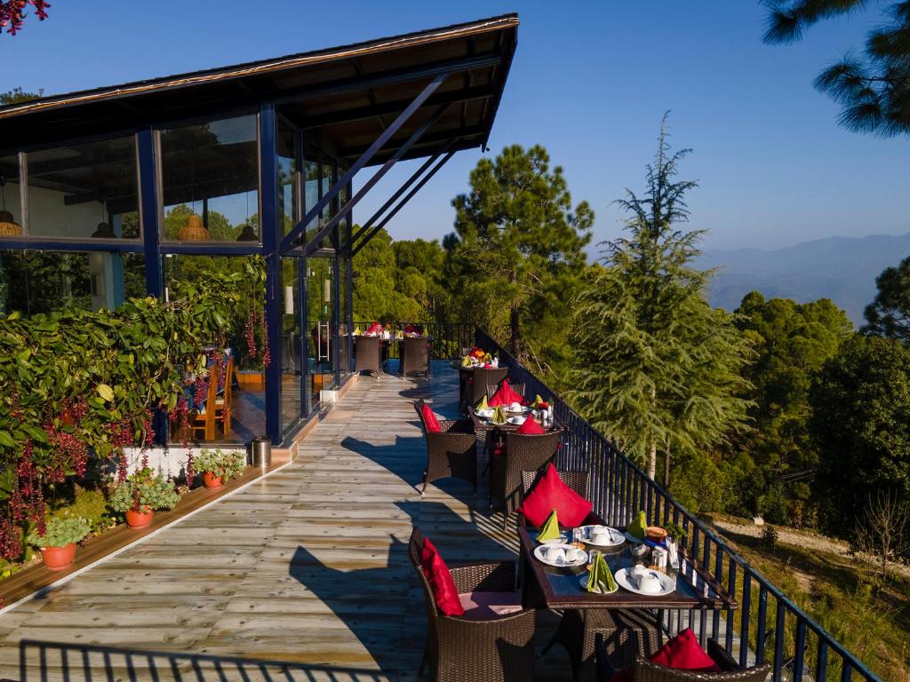 a restaurant with tables and chairs on a wooden walkway at Seed At Queens Meadows, Ranikhet in Rānīkhet