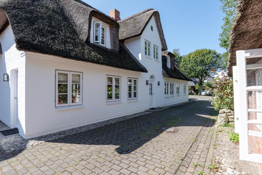 a white house with a black roof and a driveway at Kapitänshaus West in Oldsum