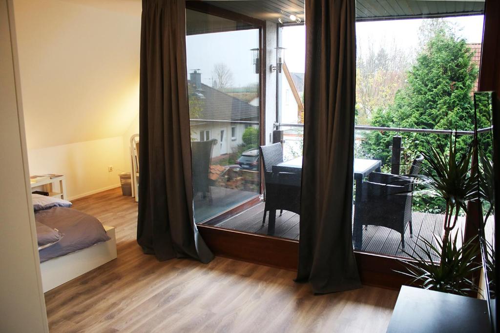 a bedroom with a large window and a balcony with a table at Messe- und Gästezimmer Hildesheim in Harsum