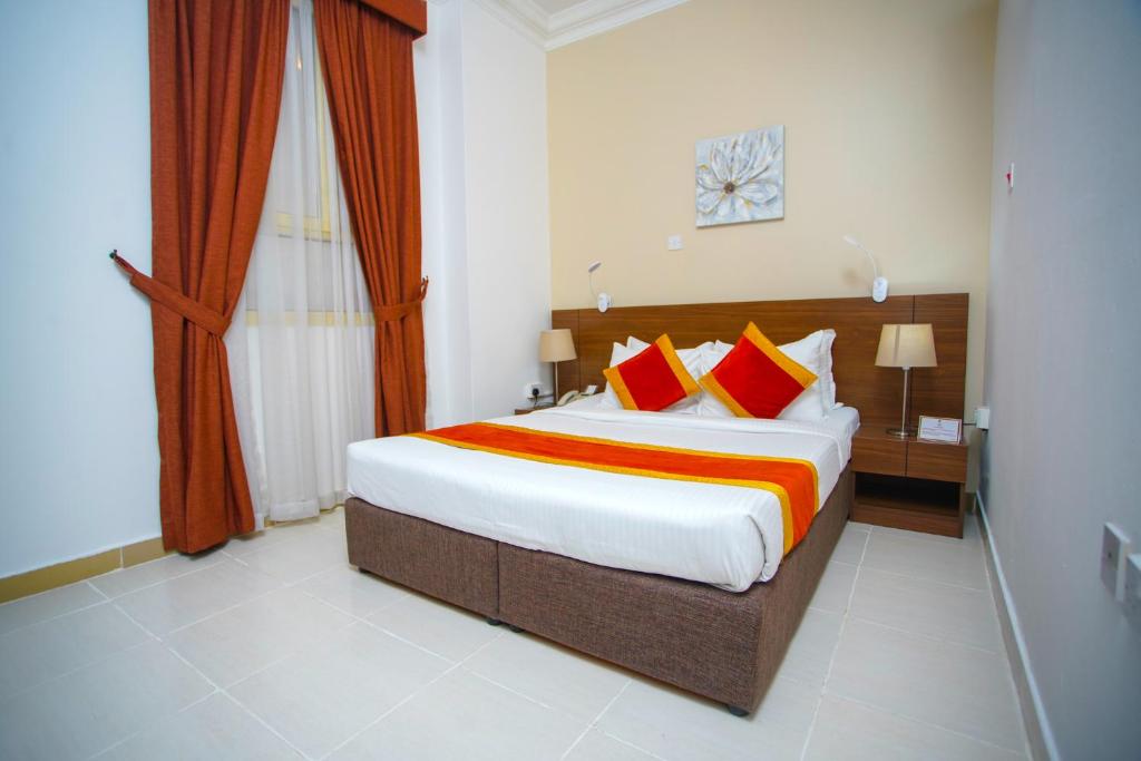 a bedroom with a large bed with red and orange pillows at La Villa Hotel in Doha