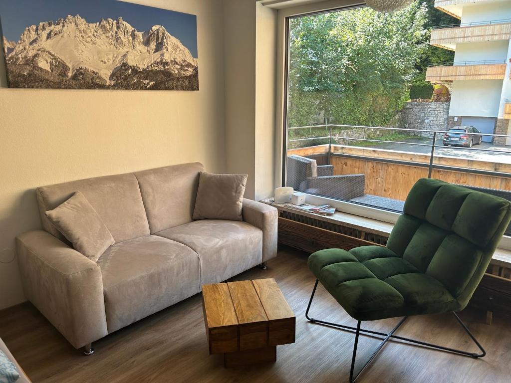 uma sala de estar com um sofá, uma cadeira e uma janela em Kitz-Studio em Kitzbühel