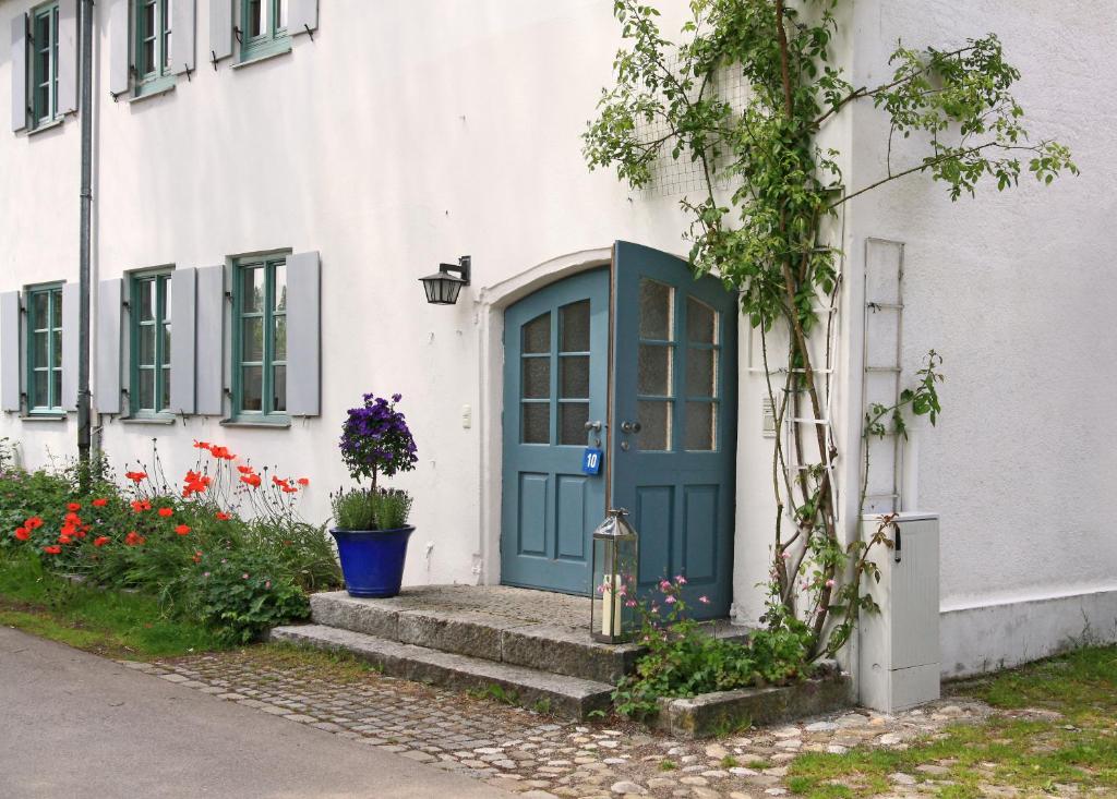 une porte bleue sur un bâtiment blanc avec des fleurs dans l'établissement DOMIZIL VIA CLAUDIA, 