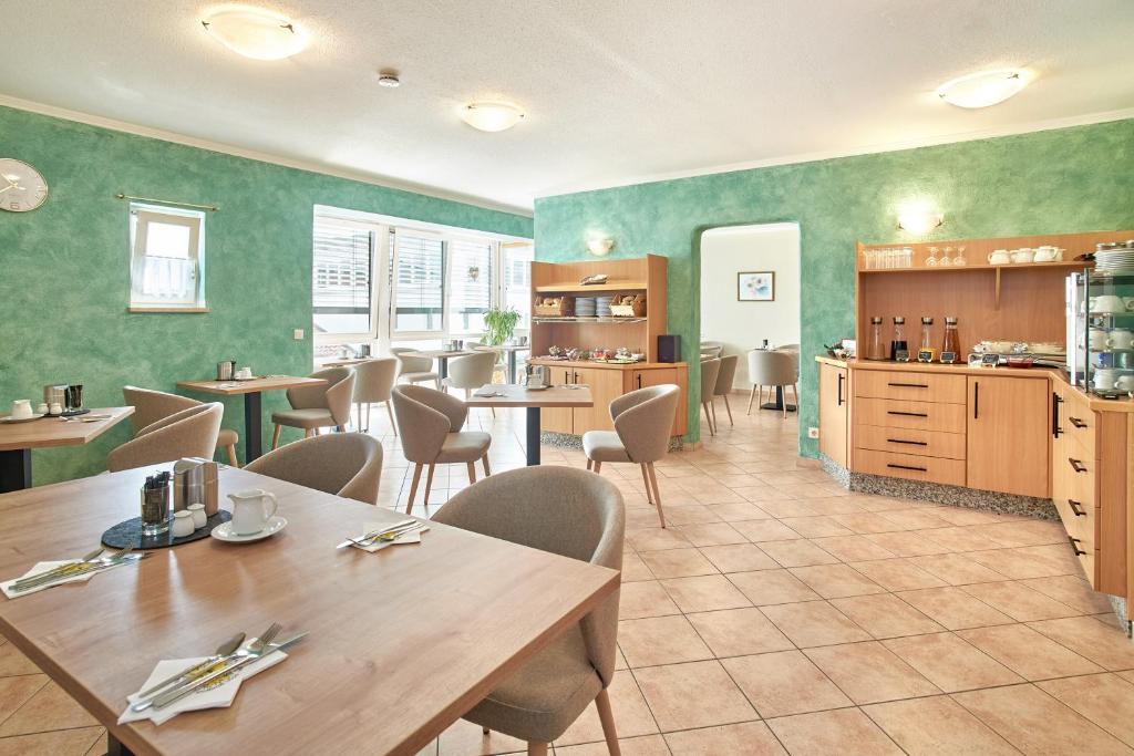 a restaurant with tables and chairs and a kitchen at Apparthotel Minerva Diana Octavia in Bad Gögging