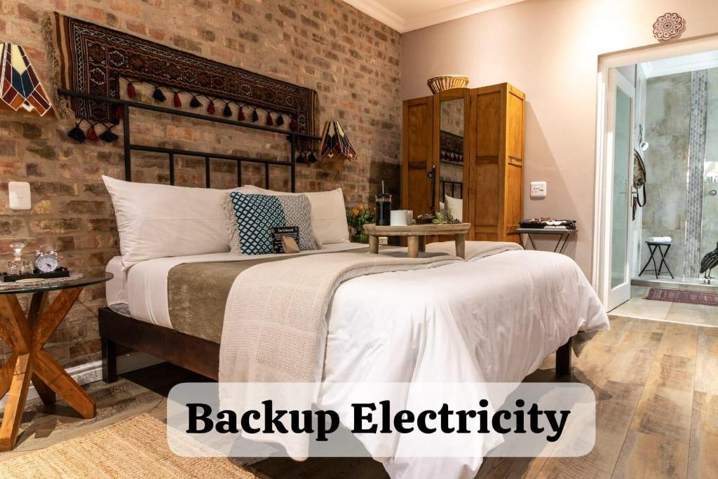 a bedroom with a large bed and a brick wall at Earthbound Guest House in Oudtshoorn