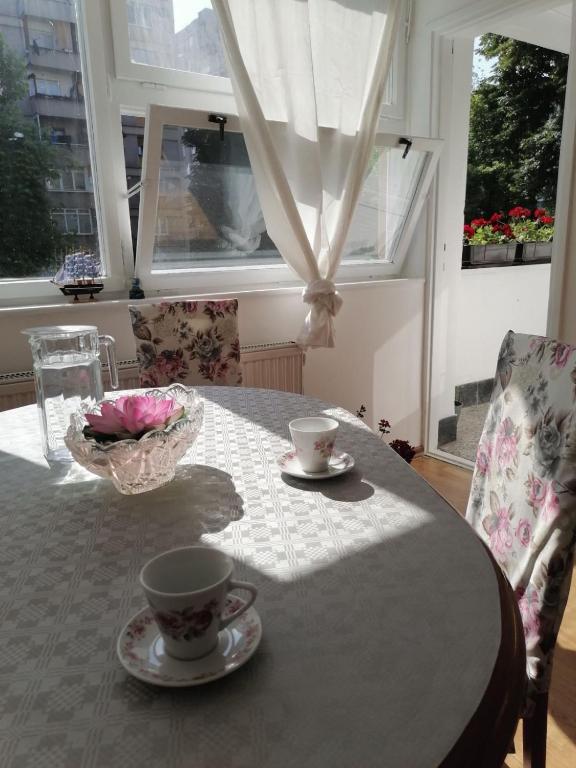 a dining room table with cups and saucers on it at Flowers Apartment Tuzla in Tuzla