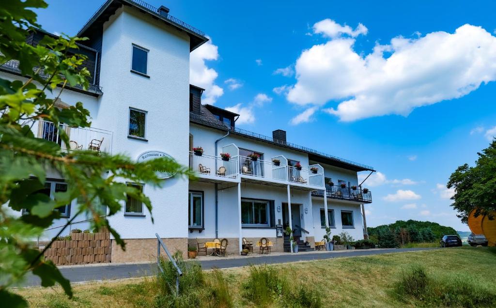 a large white building with tables and chairs at Haus Koinonia in Langscheid