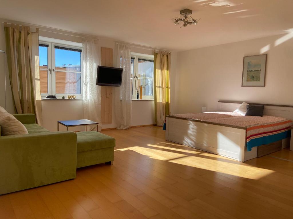 a bedroom with a bed and a couch and windows at BnB-Home Apartment in Buxheim