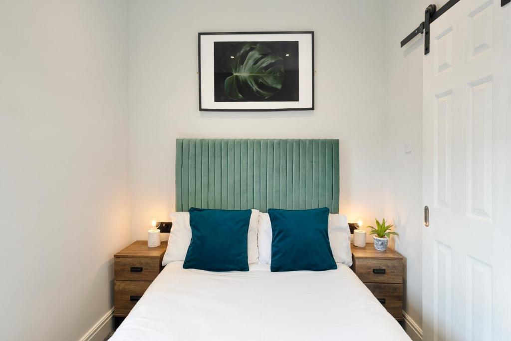 um quarto com uma cama grande e almofadas azuis em Cosy Modern Apartment With Free Parking em Cardiff