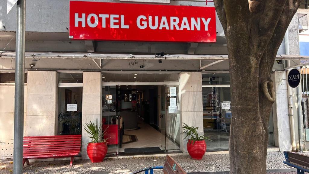 a hotel courtyard with a red bench in front of a building at Hotel Guarany da Serra in Poços de Caldas