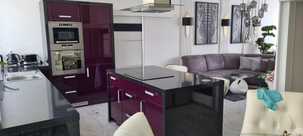 a kitchen with purple cabinets and a living room at Bordó apartmán A4 v Chomutově in Chomutov