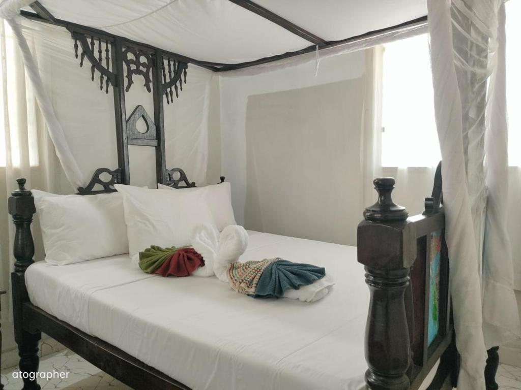 a bed with a black and white canopy bed with two pillows at Manama Suites Apartment in Lamu