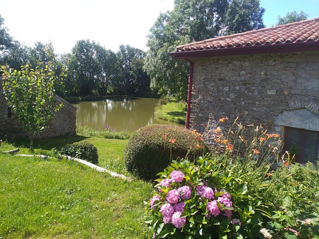 um jardim com um lago e um edifício e flores em La Petite Maison dans la Prairie em Scillé