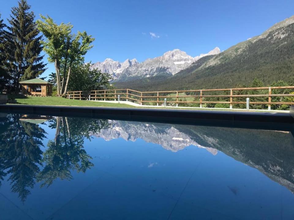 a pool with a fence and mountains in the background at Hotel Regent's in Andalo