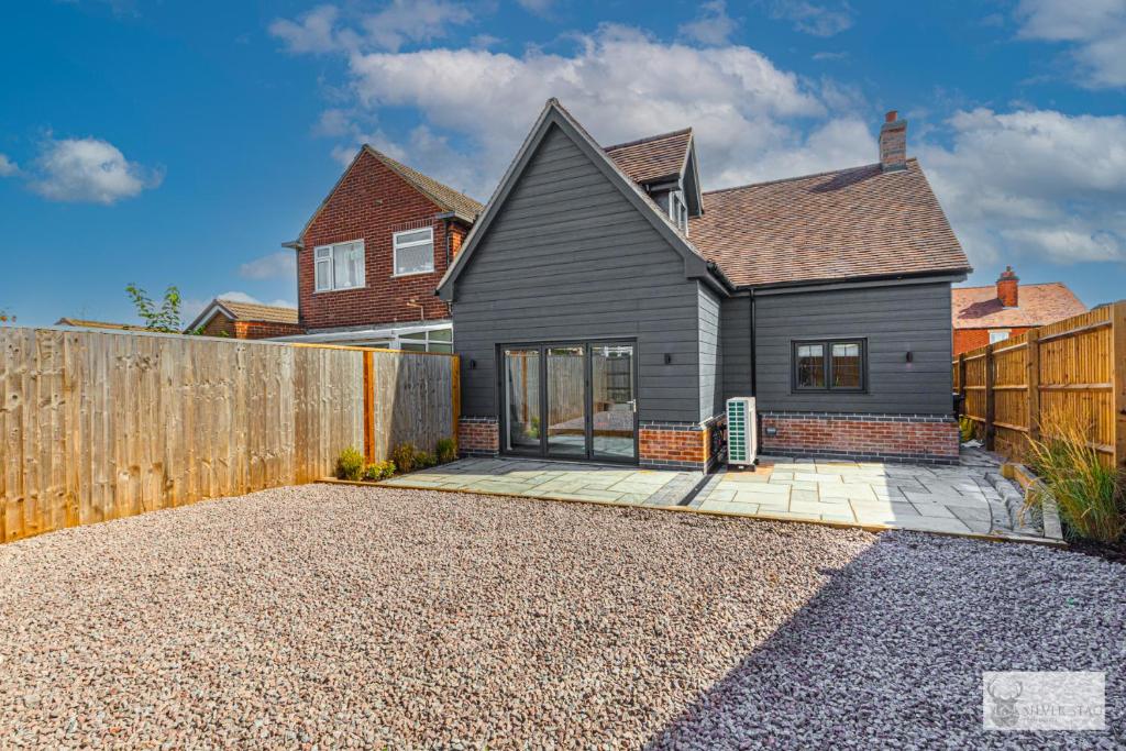 a black house with a wooden fence and a driveway at Elegant 5-Bed House with ample parking in Smisby