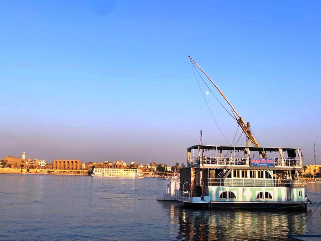 a boat with a crane on the water at Floating Hotel- Happy Nile Boat in Luxor