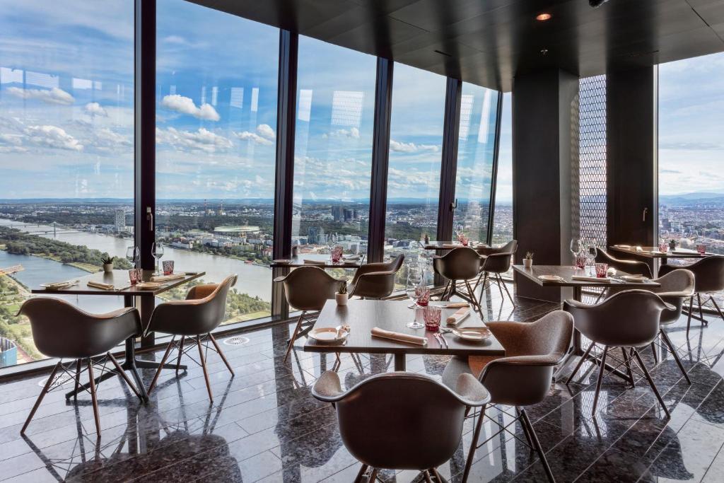 a restaurant with tables and chairs in a room with windows at Melia Vienna in Vienna
