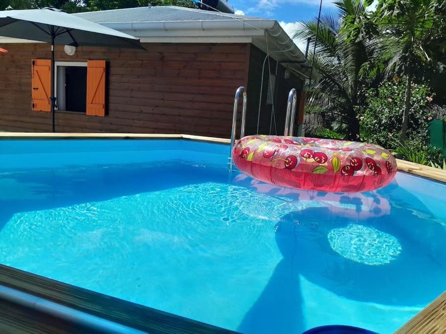 basen z czerwoną nadmuchiwaną tratwą w wodzie w obiekcie Bungalow Abricot w mieście Petit-Bourg