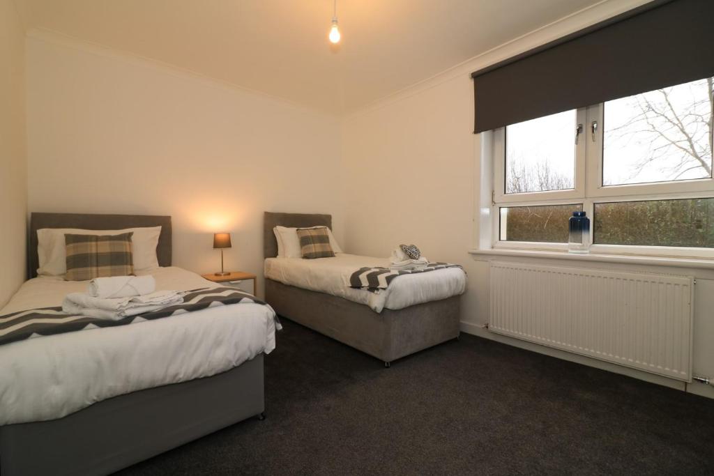 a bedroom with two beds and a window at Signature - Carrick View in Cumbernauld