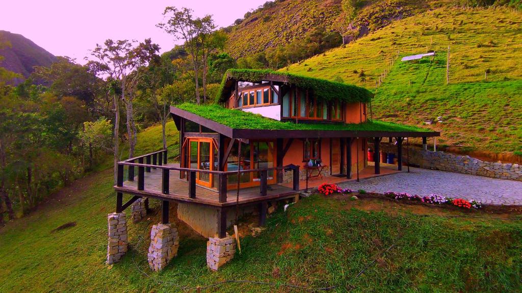 uma casa com um telhado verde numa colina em Casa Bioconstruida - Fazenda Ecológica em Nova Friburgo