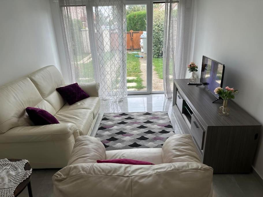 ein Wohnzimmer mit einem weißen Sofa und einem TV in der Unterkunft T2 avec jardin au calme,parking privé in Buchelay