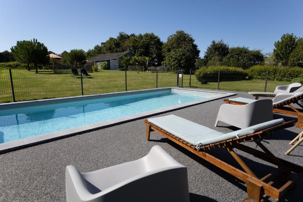 a swimming pool with two lounge chairs and a swimming pool at Appartement Calme Campagne Piscine in Clohars-Fouesnant