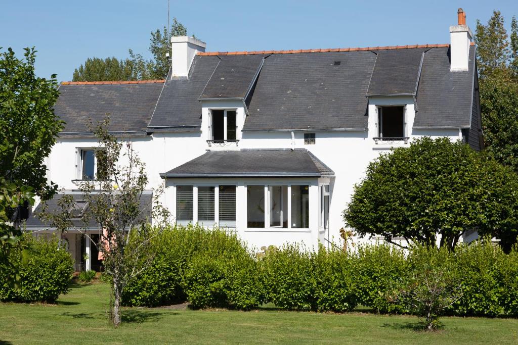 une maison blanche avec un toit noir dans l'établissement Maison Coz Campagne Calme Piscine, à Clohars-Fouesnant