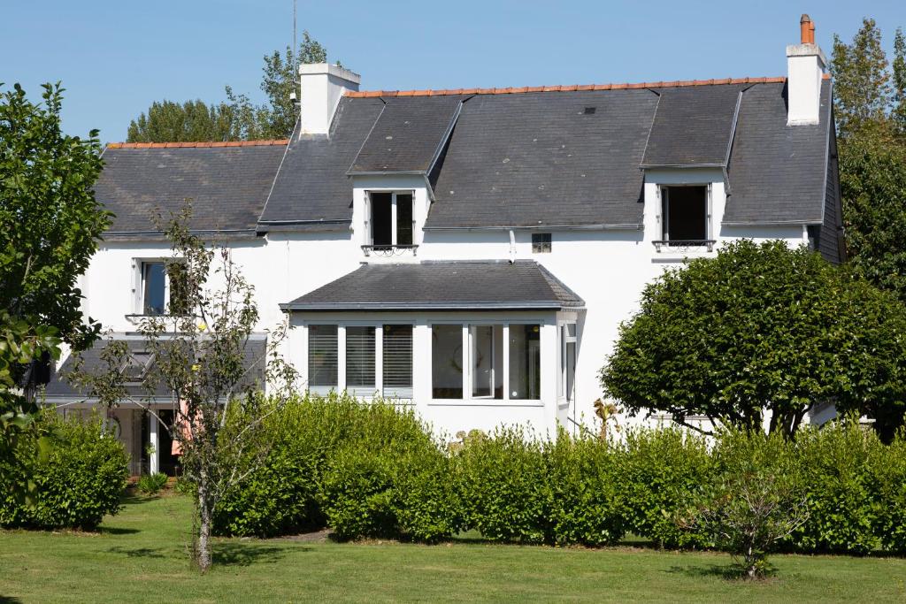 a white house with a black roof at Maison Coz Campagne Calme Piscine in Clohars-Fouesnant