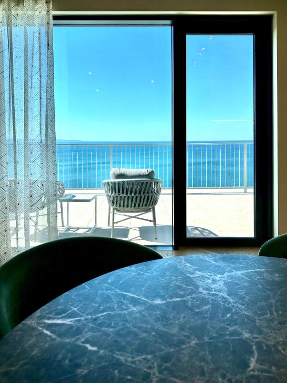 a room with a table and a chair and large windows at Maximilian Suites in Trieste