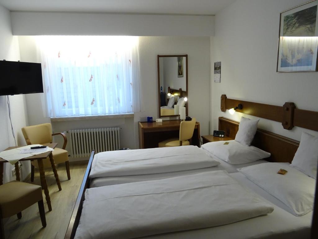una camera d'albergo con due letti, una scrivania e una finestra di Aparthotel Zum Dom a Kleinblittersdorf