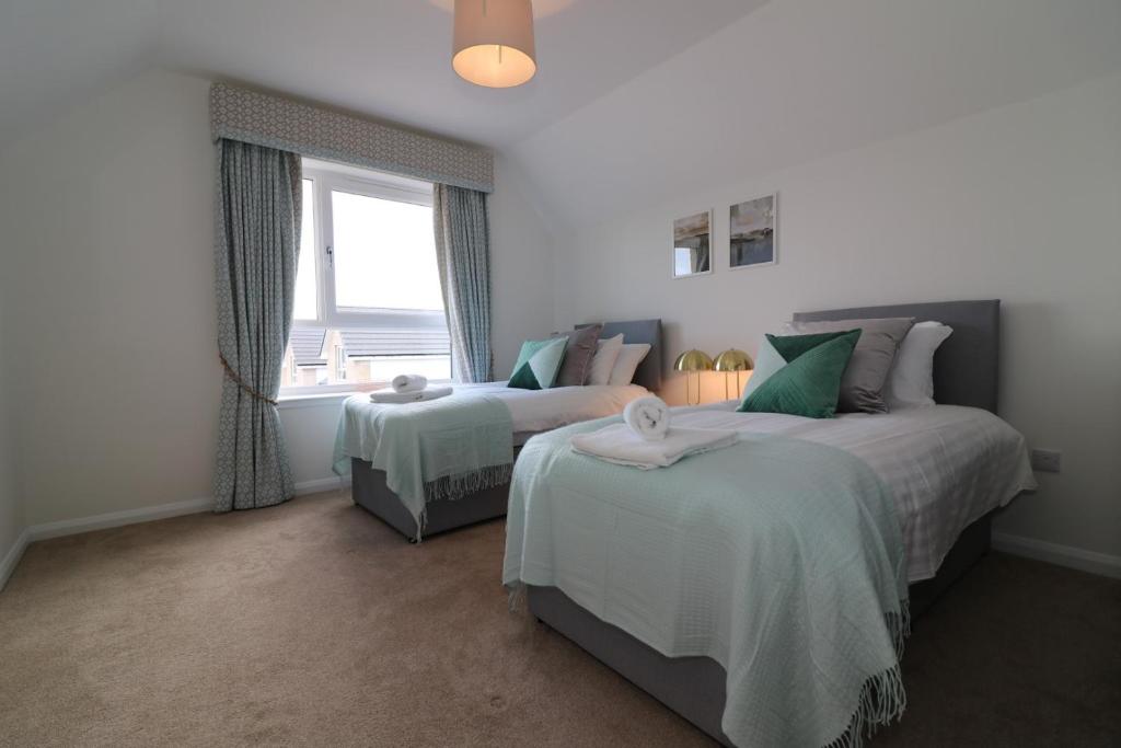a bedroom with two beds and a window at Signature - Macneish House East Kilbride in East Kilbride