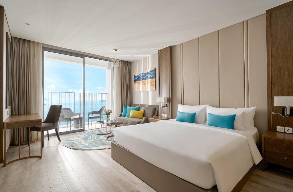 um quarto de hotel com uma cama grande e uma janela grande em OceanDream Panorama Luxury Suites em Nha Trang