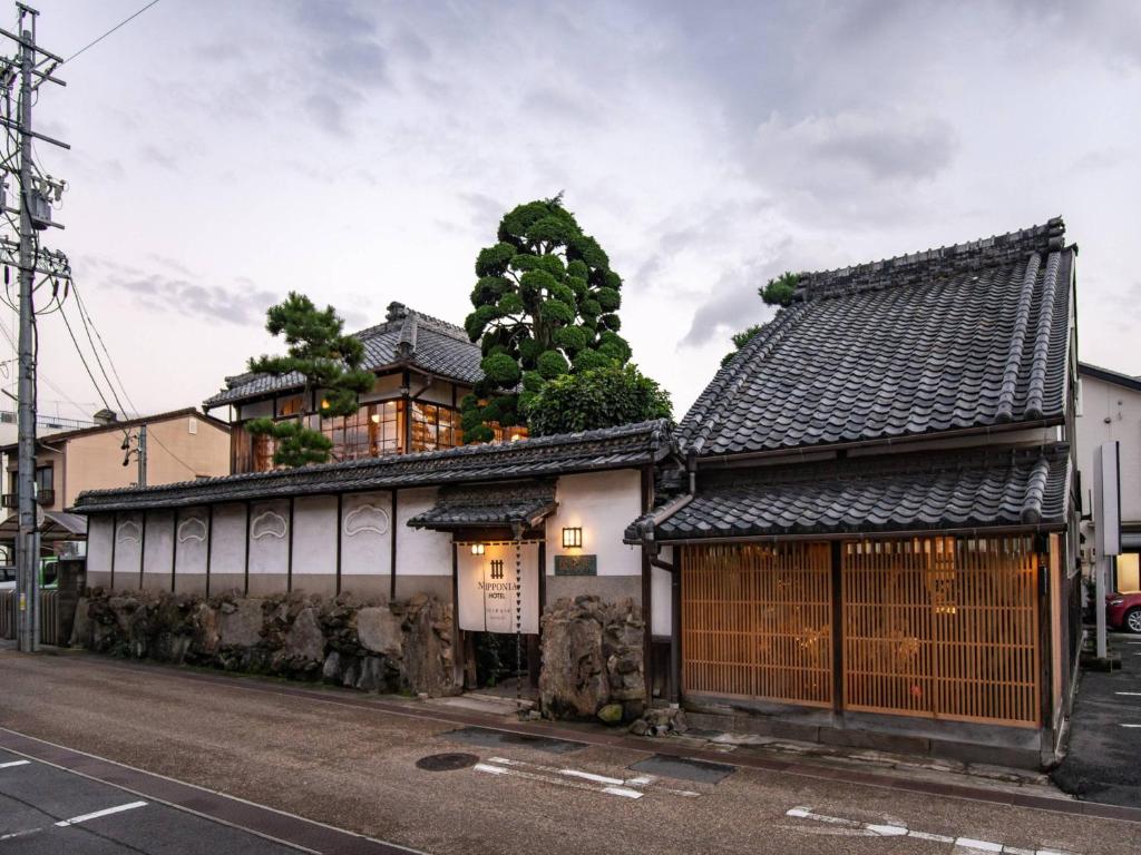 un viejo edificio con un árbol encima en NIPPONIA HOTEL 伊賀上野 城下町, en Iga