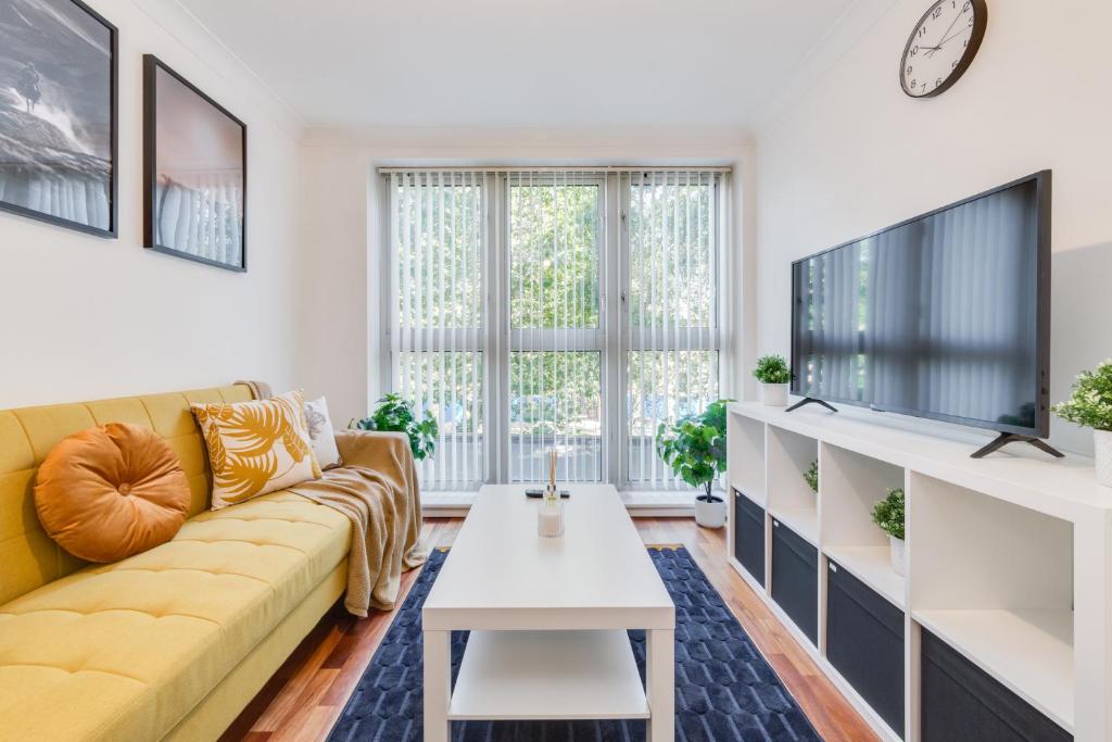 un soggiorno con divano giallo e TV di Cosy 1 Bed Apartment - Canary Wharf, Limehouse a Londra