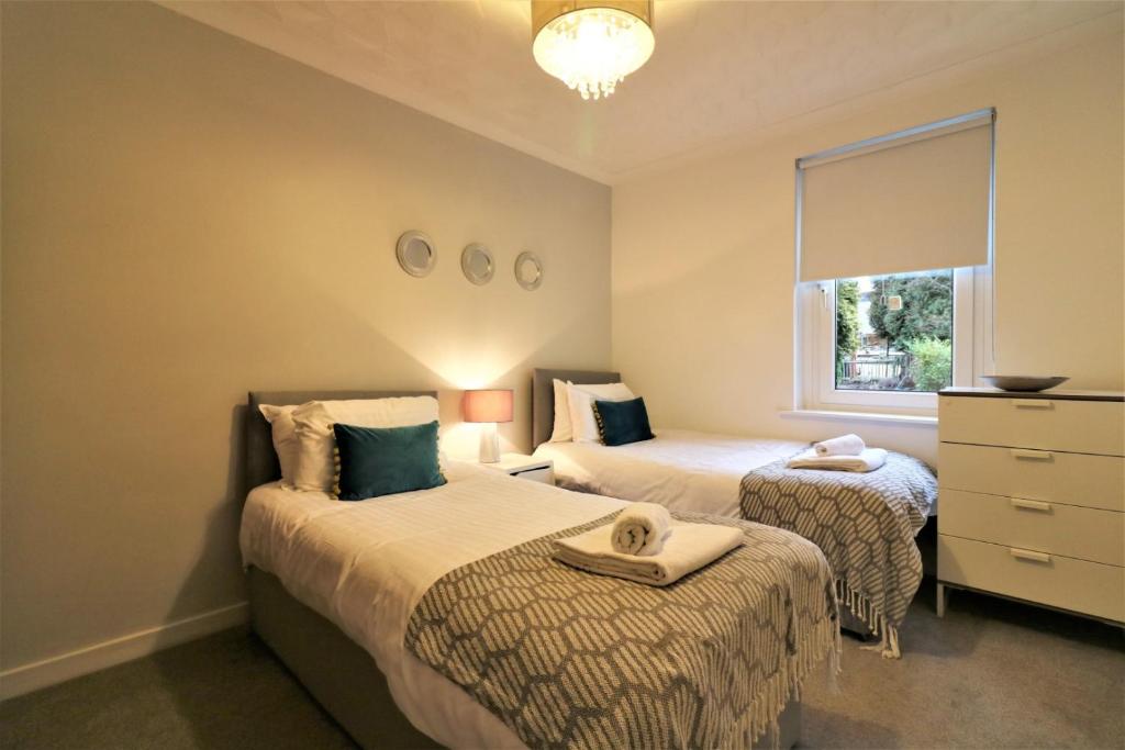 two beds in a small room with a window at Signature - Bruce Terrace Lower in High Blantyre