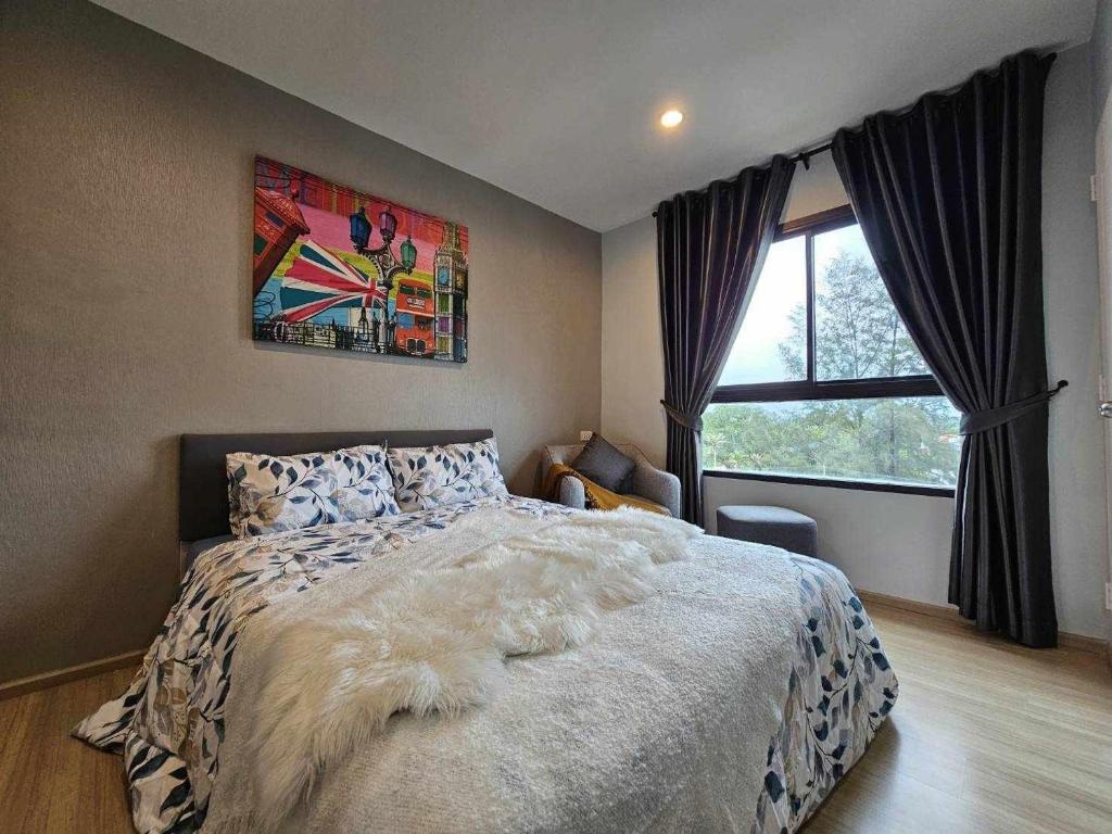 ein Schlafzimmer mit einem großen Bett und einem Fenster in der Unterkunft Zcape1 Condo Bangtao Beach in Ban Thalat Choeng Thale