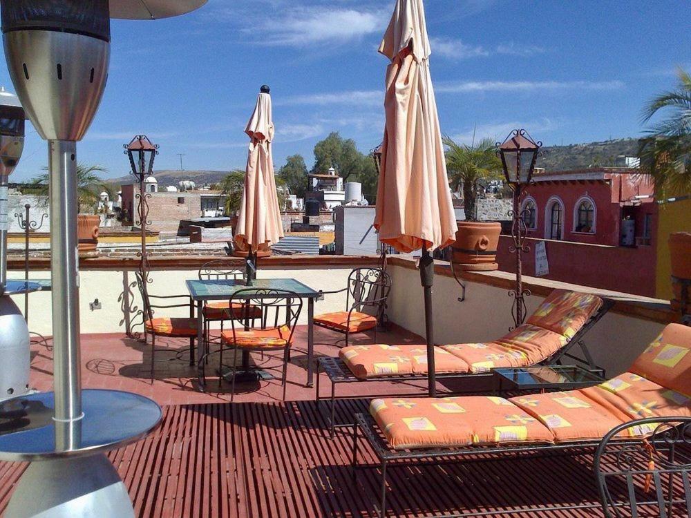um pátio com cadeiras, mesas e guarda-sóis no telhado em Hotel Antigua Casa de Piedra em San Miguel de Allende