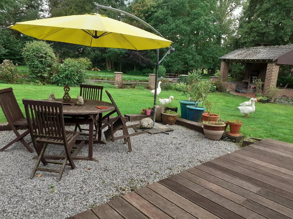 een houten tafel met een gele paraplu in een tuin bij Le Moulin des Aulnes in Hamois