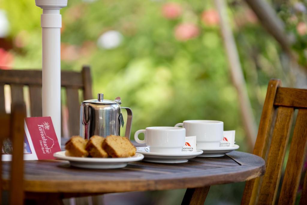 a table with two cups and plates of cookies at Tamahuche Hotel Rural in Vallehermoso