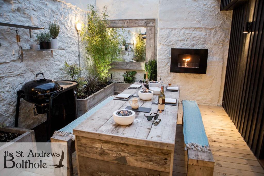 a outdoor kitchen with a wooden table and a fireplace at Luxury in the most convenient location in St Andrews in St. Andrews