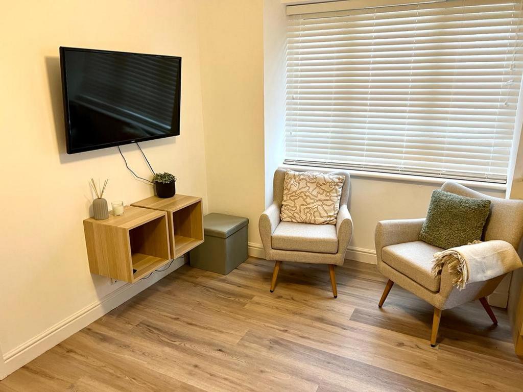 - un salon avec deux chaises et une télévision à écran plat dans l'établissement Cosy 1BD Getaway Perfect for Couples Stamford, à Stamford