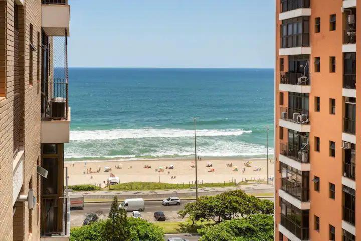 a view of a beach from between two buildings at Estúdio aconchegante frontal praia Barra - 2 suítes in Rio de Janeiro