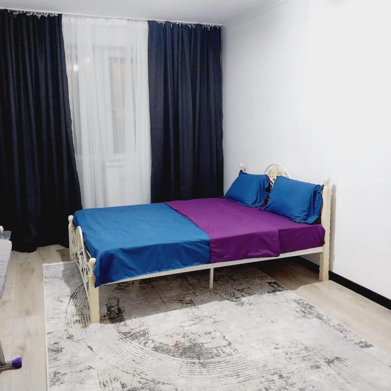 een slaapkamer met een bed met blauwe en paarse lakens bij жк Утеген in Alma-Ata