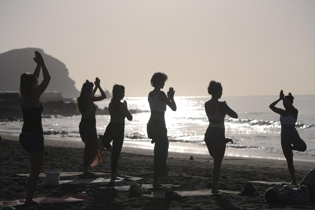 un gruppo di donne che fanno yoga sulla spiaggia di Hostel Los Amigos Yoga & Wellness a La Mareta