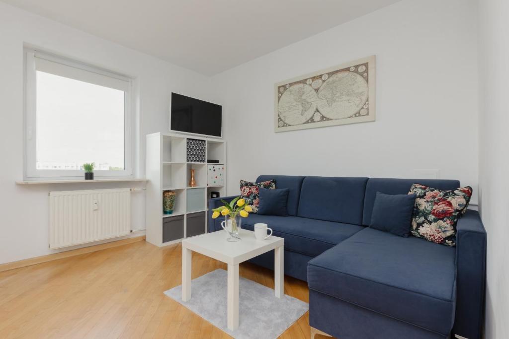 a living room with a blue couch and a table at Comfy Apartment Powstańców Śląskich by Renters in Warsaw