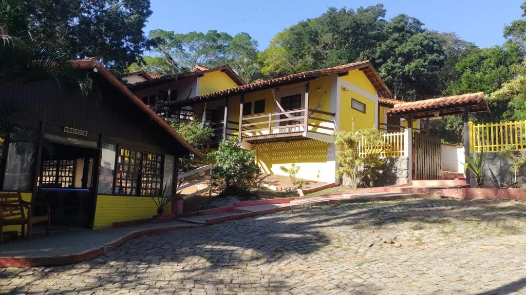 Casa amarilla con porche y entrada en Hotel Pousada Recanto das Árvores, en Búzios
