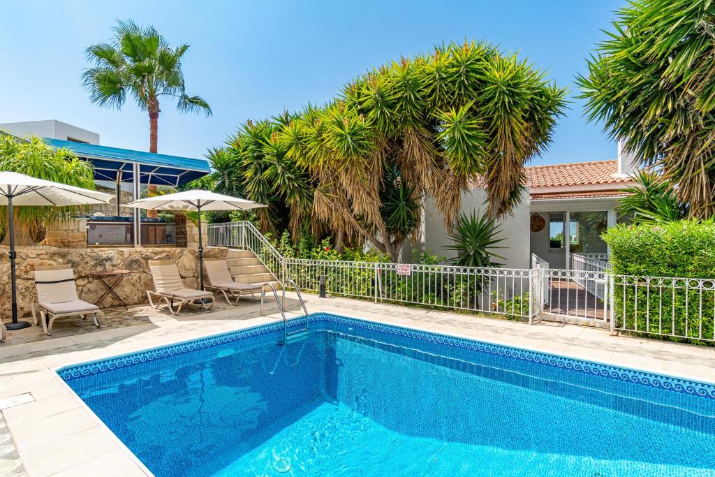 a swimming pool with palm trees and a house at The Bridge Villa by Ezoria Villas in Coral Bay