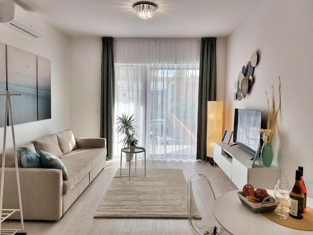 een woonkamer met een bank en een tv bij Linden Apartman 104 - Adults Only in Mosonmagyaróvár