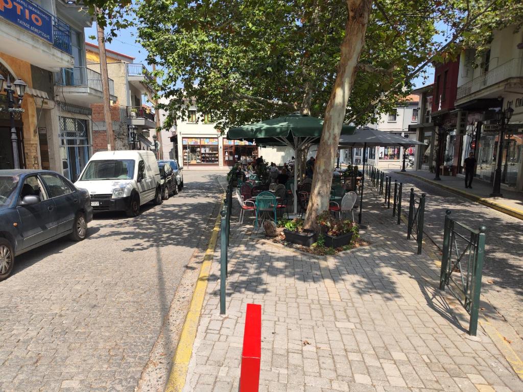 a sidewalk with tables and chairs and a tree on a street at Ονειροπαγίδα in Veria