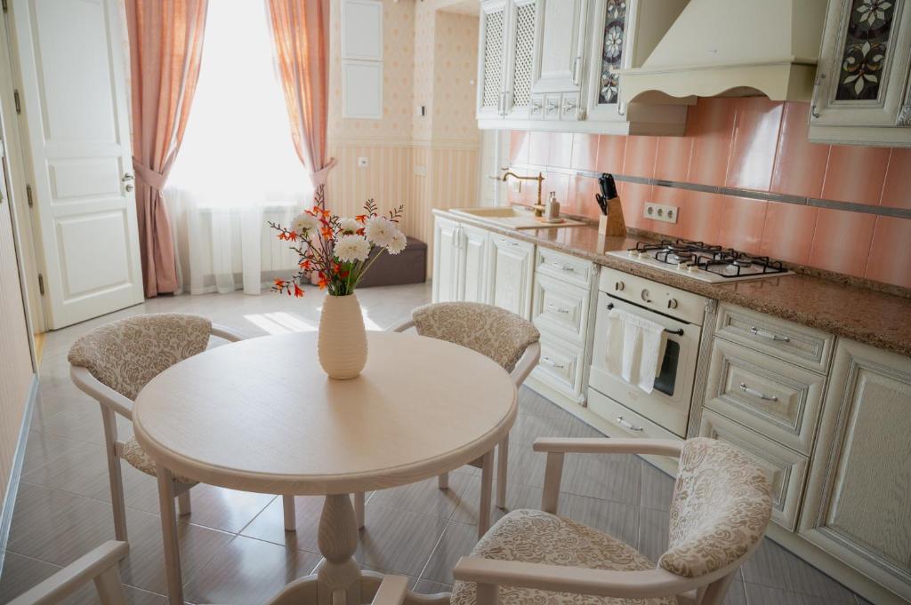 eine Küche mit einem Tisch und Stühlen sowie eine Vase mit Blumen in der Unterkunft One bedroom apartment with balcony-Kostyushka street,16 in Lwiw