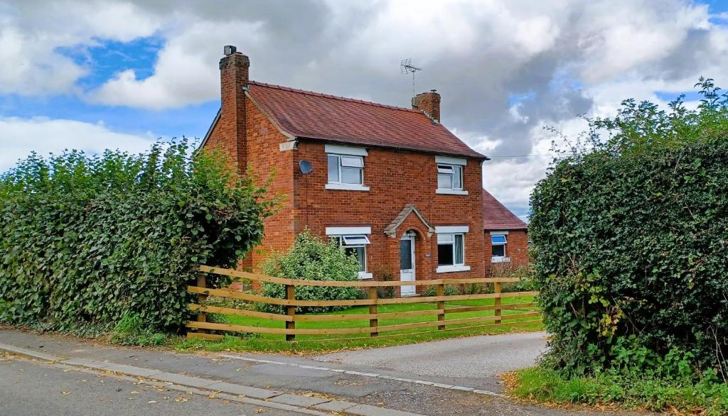 a brick house with a fence in front of it at Little Harries Cottage - surrounded by open fields in Ripon